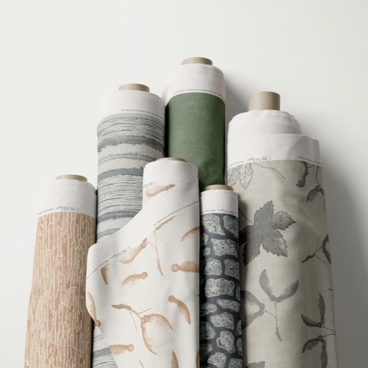 Collection of fabric rolls with various patterns and colors on a white background