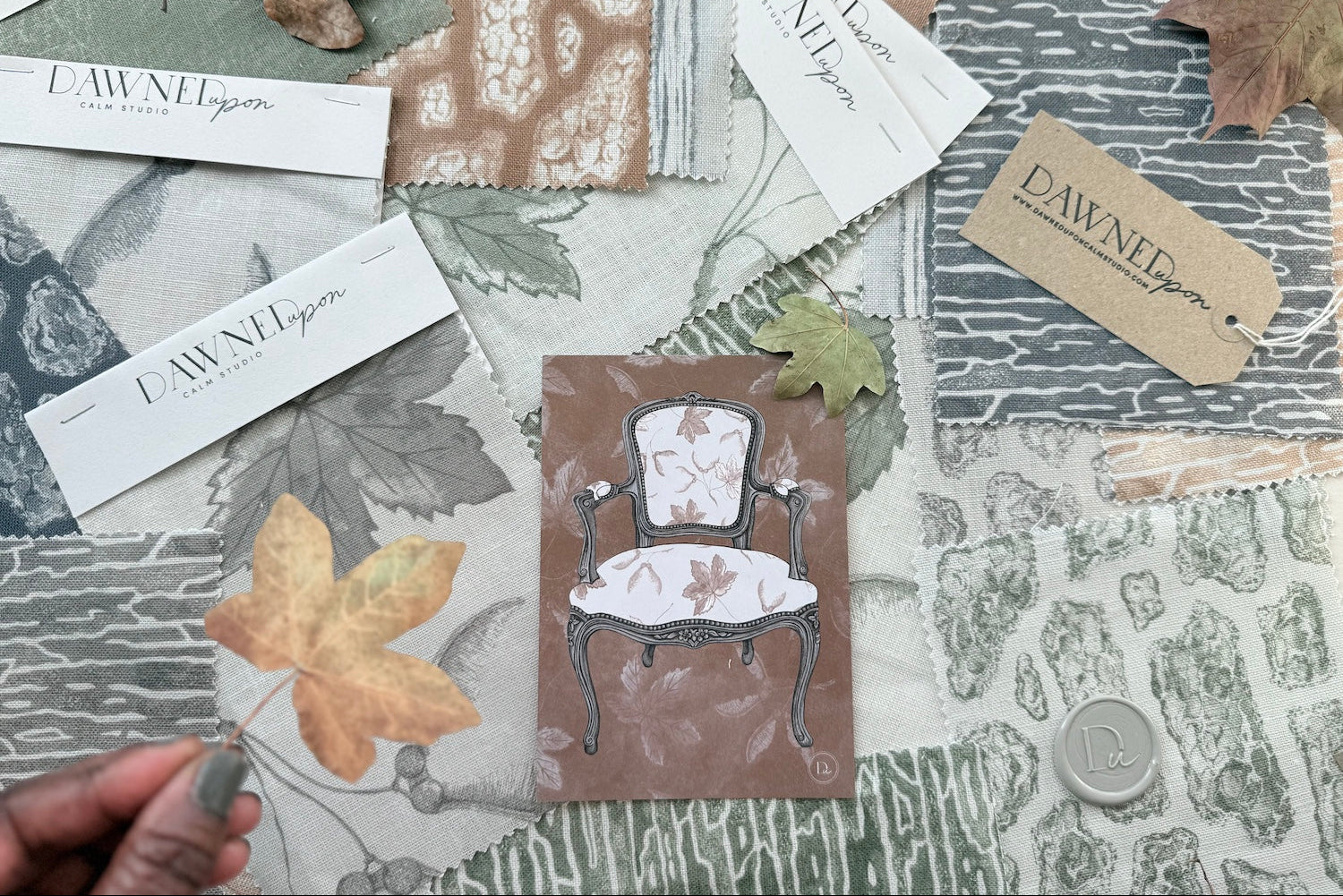 Fabric swatches featuring DawnedUpon Calm Studio's branding and leaf designs, along with a Chair illustration postcard.  